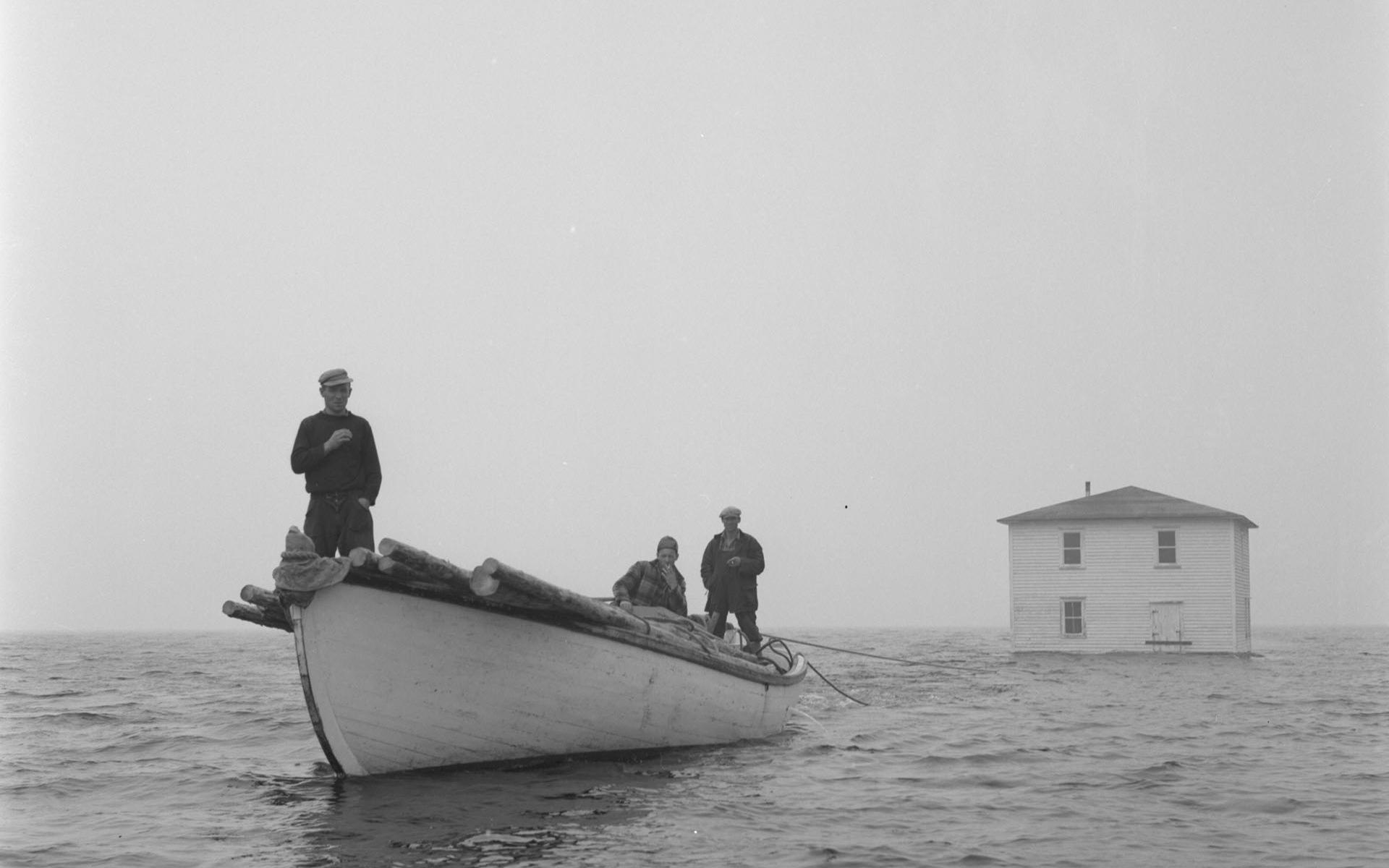Newfoundland outport house being towed by fishing boat