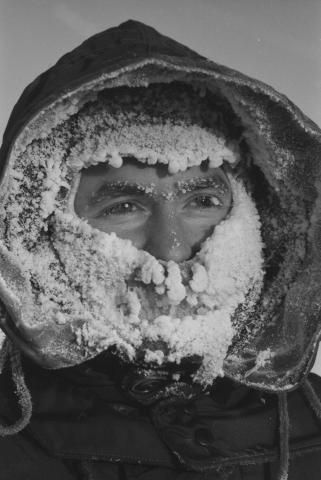 Hydrographer Ralph Courtnage with breath-encrusted parka hood and face-mask while at work out on sea ice
